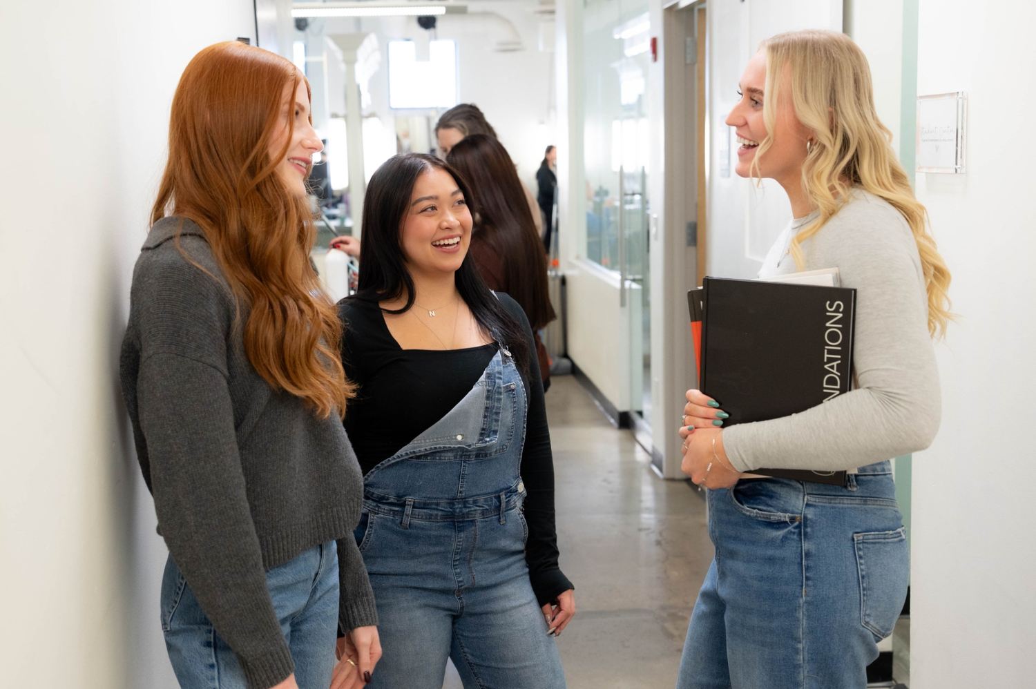 Three people speaking together in a school hallway
